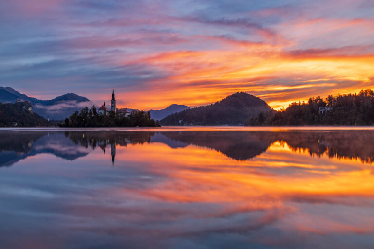 Sun rising over Lake Bled and the island church of the assumption of Mary with the Karavanke mountains in the background, Slovenia.