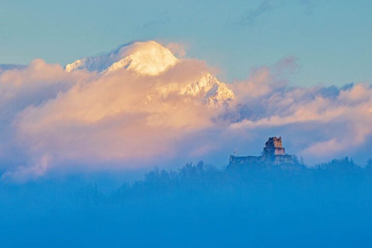 View across to Smlednik Castle and Storzic mountain, part of the Kamnik Alps, as the morning fog clears at sunrise.