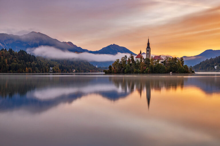 View across Lake Bled to the island church and clifftop castle in all it's autumn glory, Slovenia.