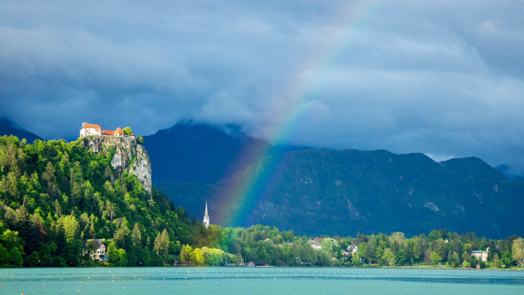 Rainbow over Lake Bled Beautiful light across to the beautiful Lake Bled's hilltop castle and Church of Saint Martin as a storm blows over and produces a rainbow. Slovenia.