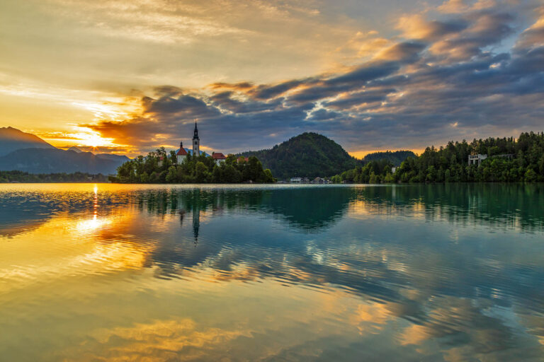 Sun rising over Lake Bled and the island church of the assumption of Mary with the Karavanke mountains in the background, Slovenia.