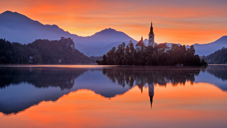 Summer sunrise over Lake Bled and the island church of the assumption of Mary with the Karavanke mountains in the background, Slovenia.