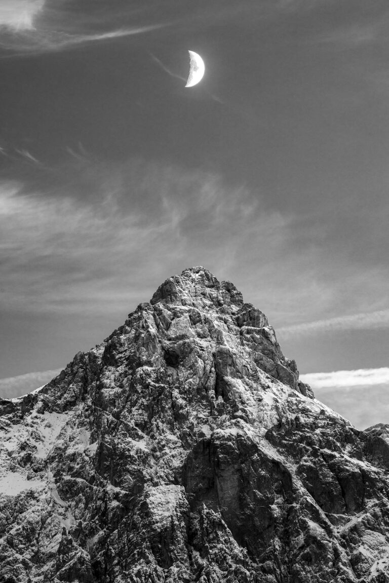 Quarter moon rising over Mount Razor in the Julian Alps mountains of Slovenia. Seen from Lake Jasna near Kranjska Gora.