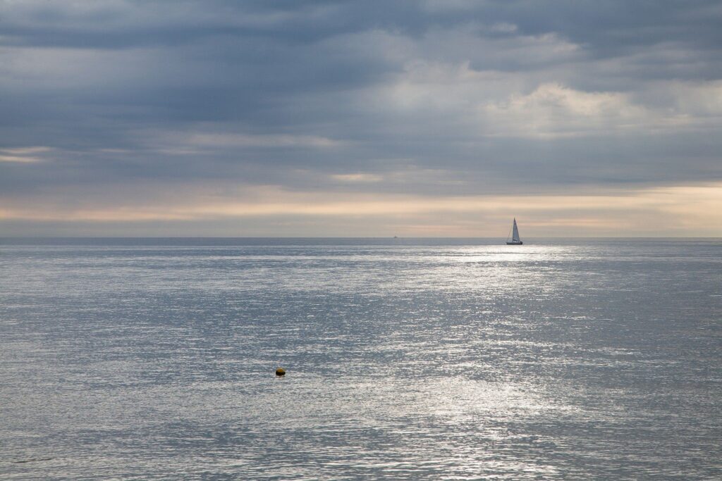 Beautiful light breaks through the clouds as a sailing boat passes by on an otherwise empty sea at Kingsdown, Kent, England.